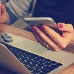 Budgeting for investments - woman holding cellphone and using laptop