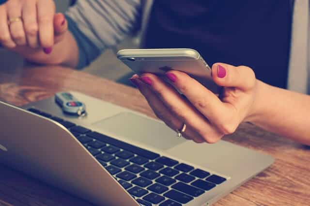 Budgeting for investments - woman holding cellphone and using laptop