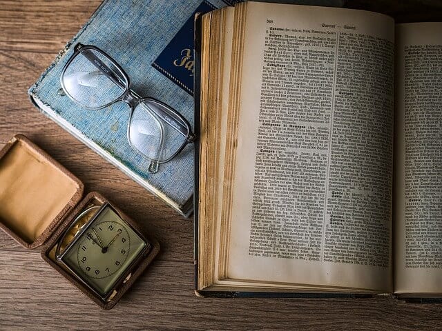 Wisdom quotes photo showing an open book with a pair of glasses. The photo is an allusion to the growth in knowledge from reading.